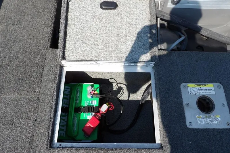 Slide: The Image of Open battery compartment in 2012 Lund 1775 Impact Sport boat, showing green Interstate battery. - 17