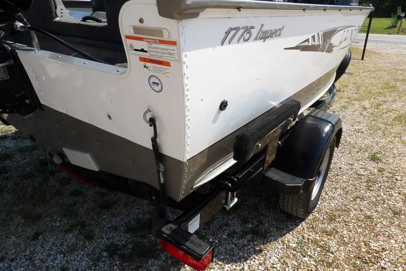 Slide: The Image of 2012 Lund 1775 Impact Sport boat on trailer, rear view, parked on gravel. - 58