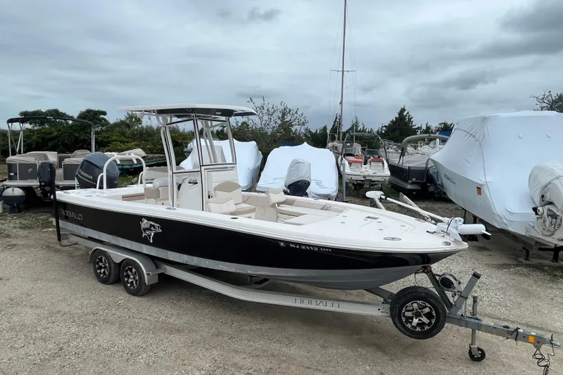 Slide: The Image of 2016 Robalo 246 Cayman boat on trailer, parked outdoors under cloudy sky. - 0