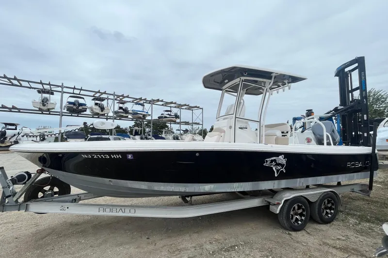 Slide: The Image of 2016 Robalo 246 Cayman boat on trailer, parked in marina with other boats. - 2