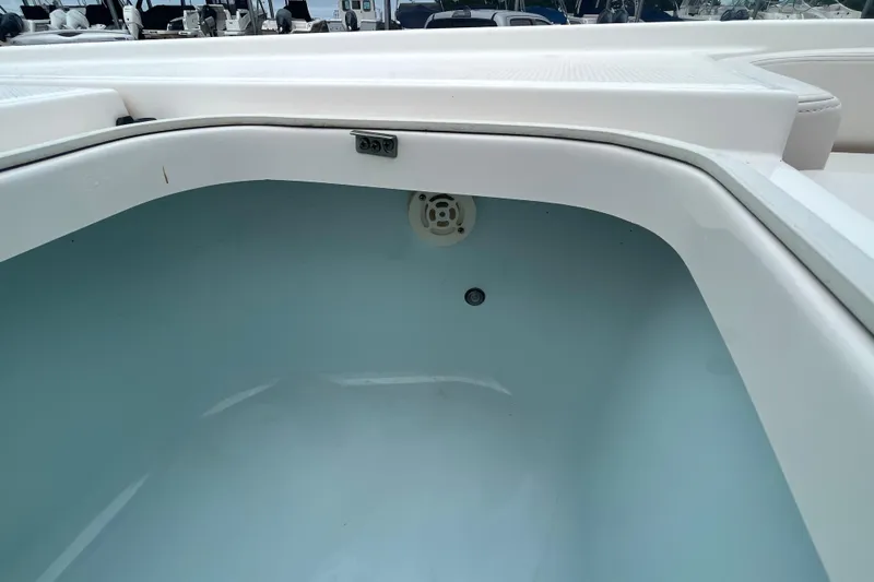 Slide: The Image of 2016 Robalo 246 Cayman boat storage compartment, white interior, open lid. - 28