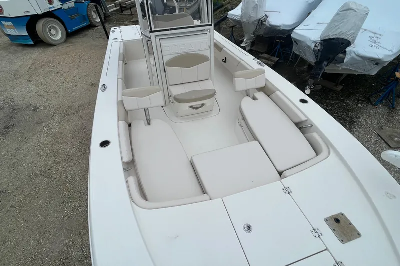 Slide: The Image of 2016 Robalo 246 Cayman boat interior with white seating and console, parked on gravel. - 31