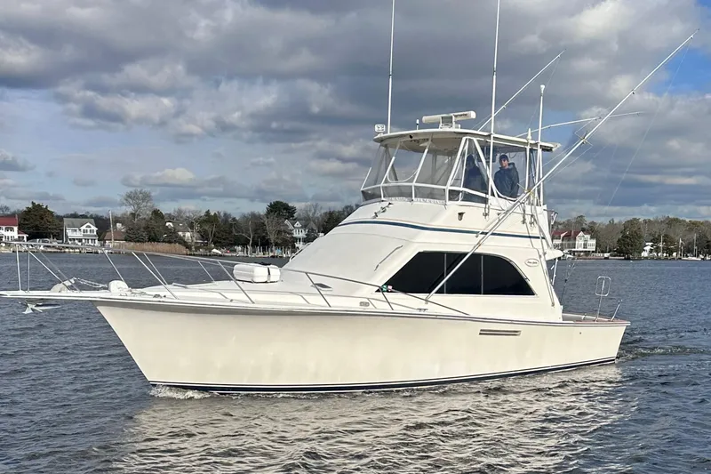 The Image of 1986 Ocean Yachts 38 Super Sport cruising on a calm river under cloudy skies. - 0