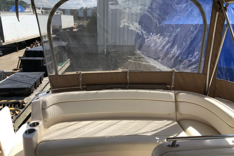 Slide: The Image of 2004 Rinker Fiesta Vee 312 boat interior with beige seating and clear canopy. - 10