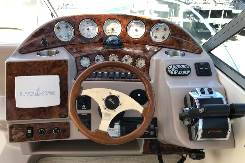 Slide: The Image of 2004 Rinker Fiesta Vee 312 boat dashboard with wood finish and navigation controls. - 14