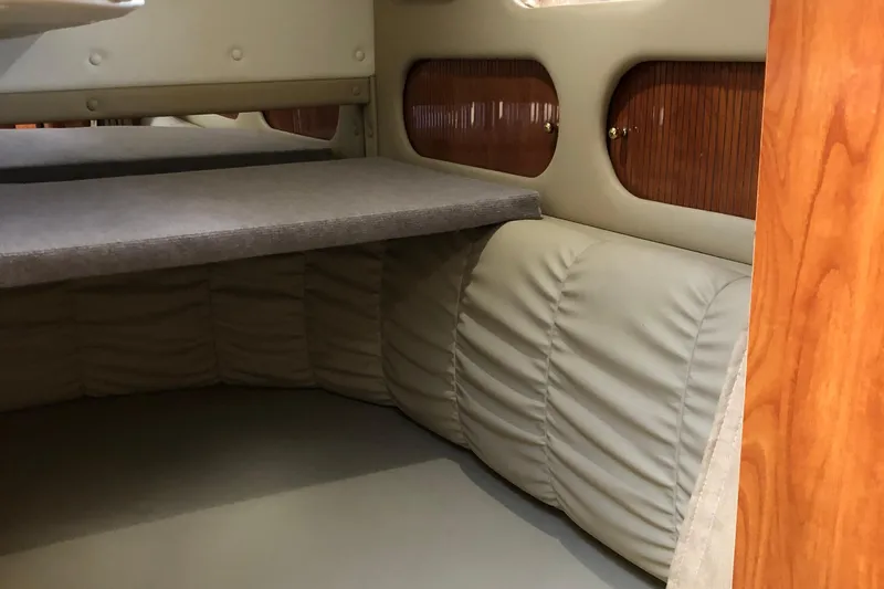 Slide: The Image of Interior cabin of 2004 Rinker Fiesta Vee 312 boat, featuring cushioned seating and wooden accents. - 24