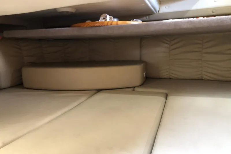 Slide: The Image of 2004 Rinker Fiesta Vee 312 cabin interior with beige cushions and storage space. - 25