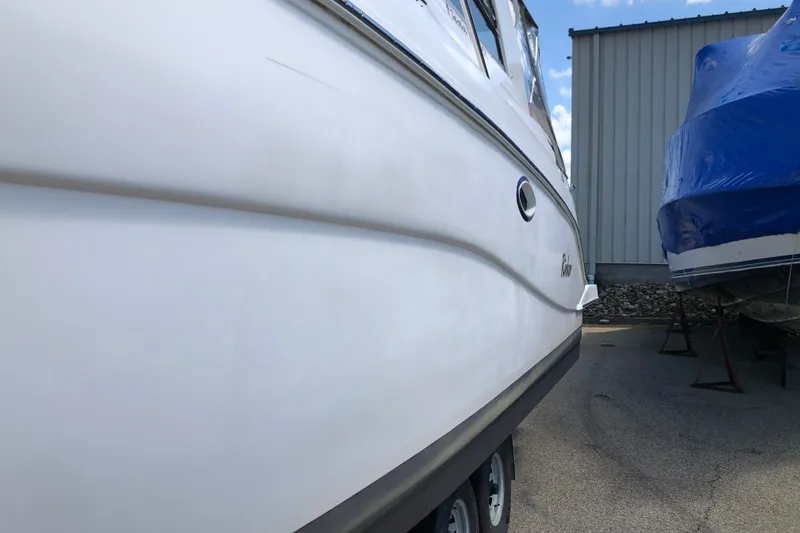 Slide: The Image of 2004 Rinker Fiesta Vee 312 boat parked beside a blue-covered vessel. - 3