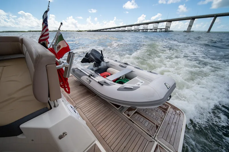Slide: The Image of 2016 Sea Ray 400 Sundancer with inflatable boat on deck, cruising under a bridge. - 10