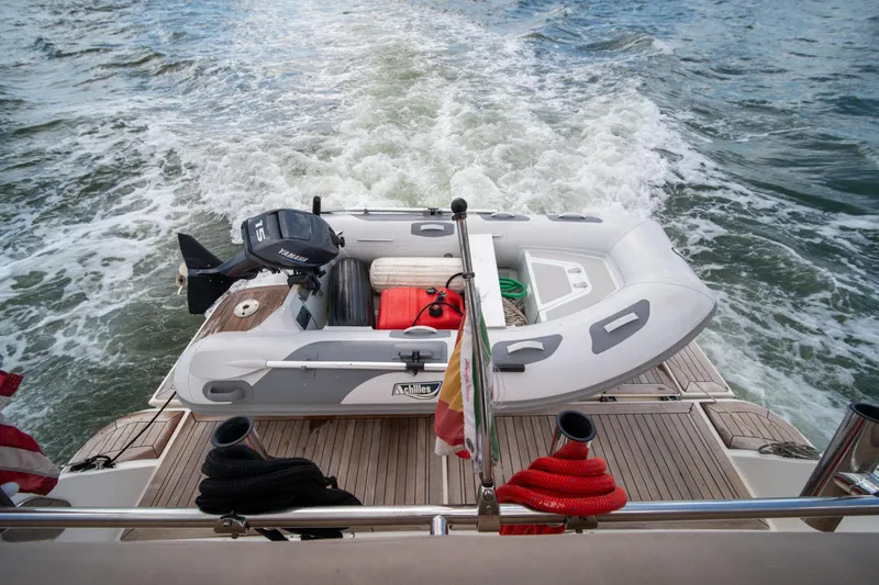 Slide: The Image of 2016 Sea Ray 400 Sundancer with inflatable boat on deck, cruising on open water. - 9