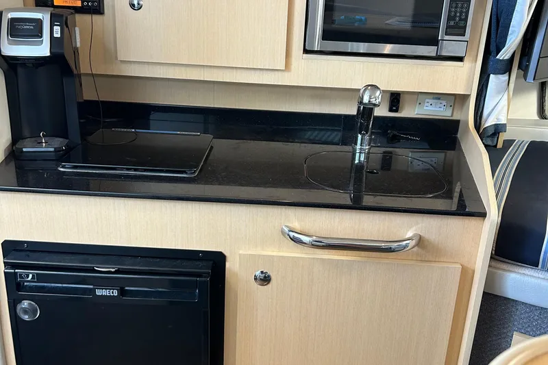Slide: The Image of Compact kitchen area in a 2011 Bayliner 285 Cruiser with sink, microwave, and mini fridge. - 18