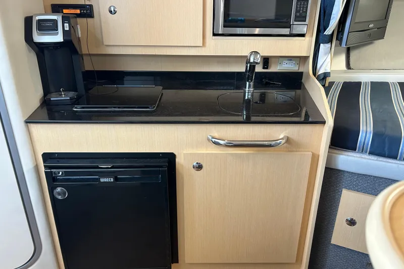 Slide: The Image of Compact kitchen area in a 2011 Bayliner 285 Cruiser with appliances and storage. - 19
