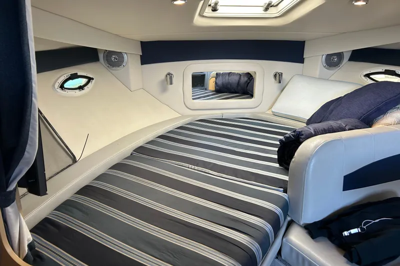 Slide: The Image of Interior cabin of 2011 Bayliner 285 Cruiser with striped bedding and porthole windows. - 21