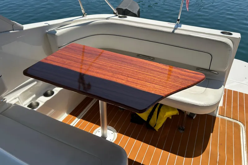 Slide: The Image of 2011 Bayliner 285 Cruiser interior with wooden table and cushioned seating. - 4