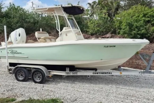 Slide: The Image of 2019 Pioneer 202 Islander boat on trailer, parked outdoors with lush greenery background. - 4