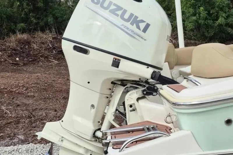 Slide: The Image of 2019 Pioneer 202 Islander with Suzuki outboard motor, beige seating, and wooded backdrop. - 8