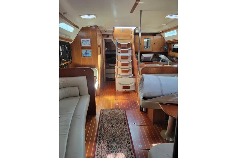 Slide: The Image of Interior of 1999 Catalina 470 yacht with wooden flooring and cozy seating area. - 18