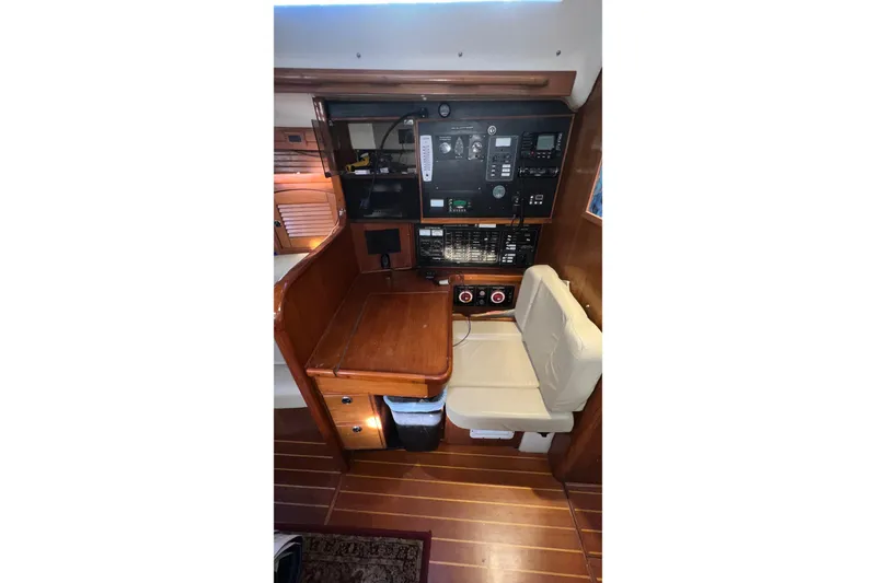 Slide: The Image of Navigation station inside 1999 Catalina 470 yacht with control panels and seating. - 26