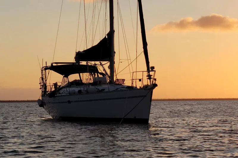 Slide: The Image of Sailboat Catalina 470, 1999 model, silhouetted against a serene sunset on the water. - 6
