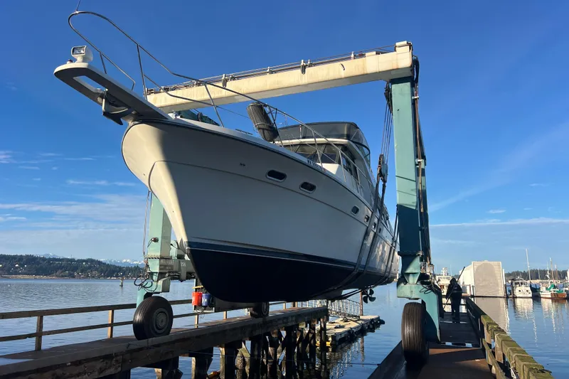 Slide: The Image of 1999 Bayliner 4788 Pilot House Motoryacht lifted by crane at marina dock. - 6