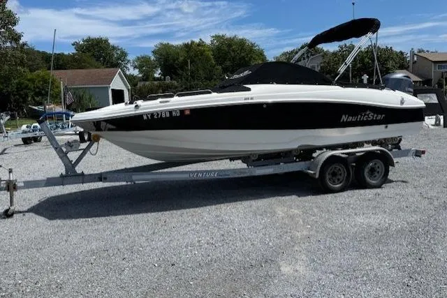 The Image of 2017 NauticStar 203DC Sport Deck boat on trailer, parked outdoors. - 0