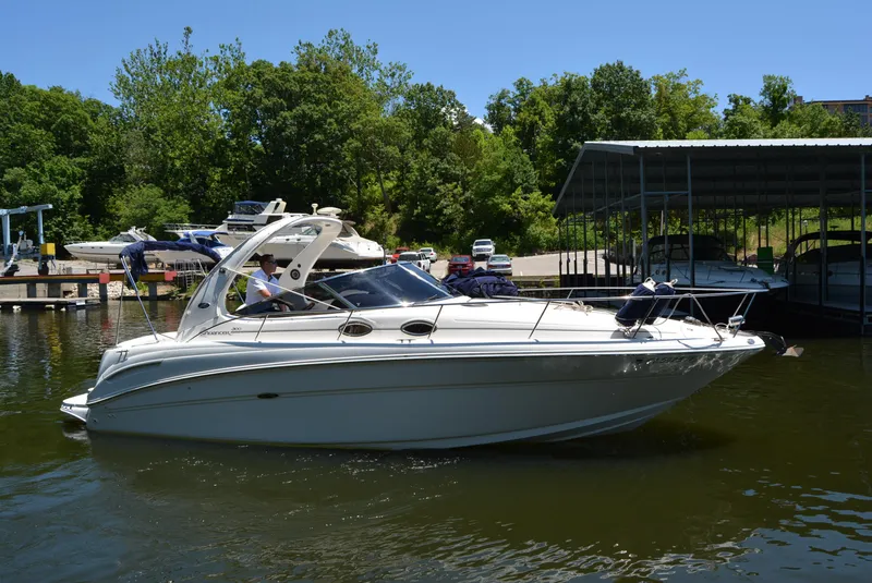 Slide: The Image of 2004 Sea Ray 300 Sundancer boat docked on a sunny day with lush greenery. - 10