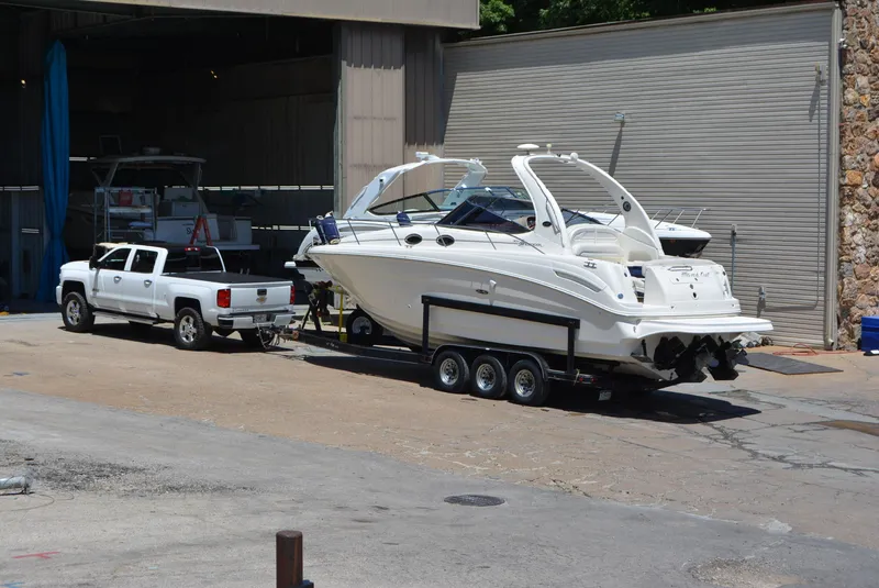 Slide: The Image of 2004 Sea Ray 300 Sundancer on trailer, towed by white truck near storage facility. - 11