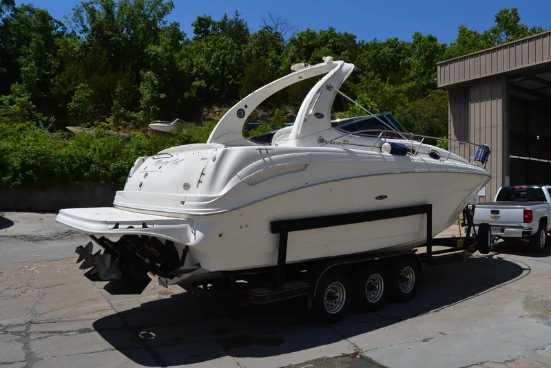 Slide: The Image of 2004 Sea Ray 300 Sundancer boat on trailer, parked outdoors near trees and building. - 17