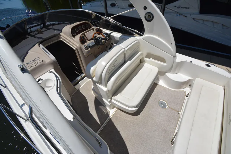 Slide: The Image of 2004 Sea Ray 300 Sundancer cockpit with seating and helm, showcasing luxury boat interior. - 30