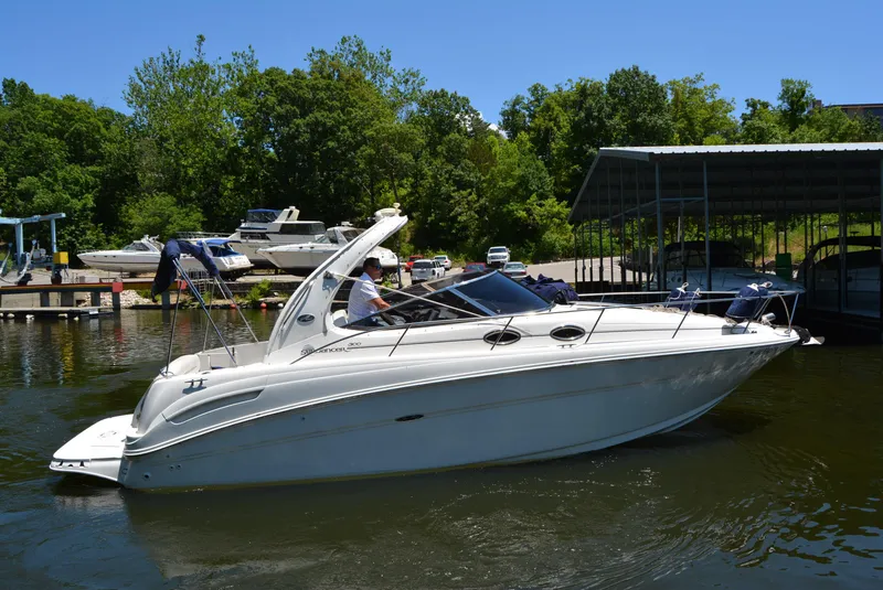 Slide: The Image of 2004 Sea Ray 300 Sundancer boat docked on a sunny day with lush greenery. - 4