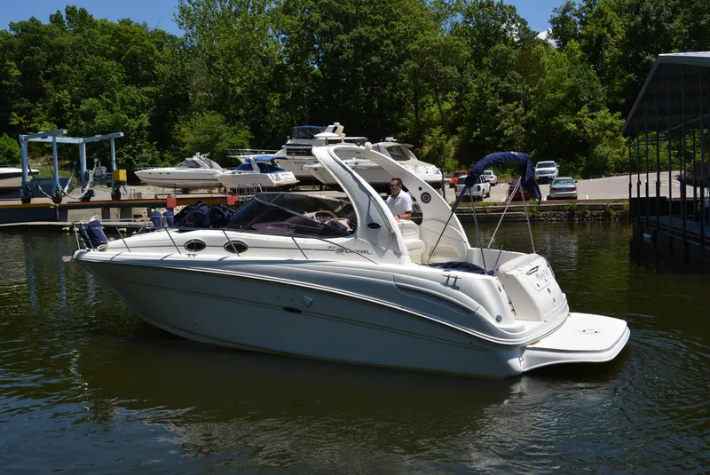 Slide: The Image of 2004 Sea Ray 300 Sundancer boat docked on a sunny day, surrounded by lush greenery. - 5