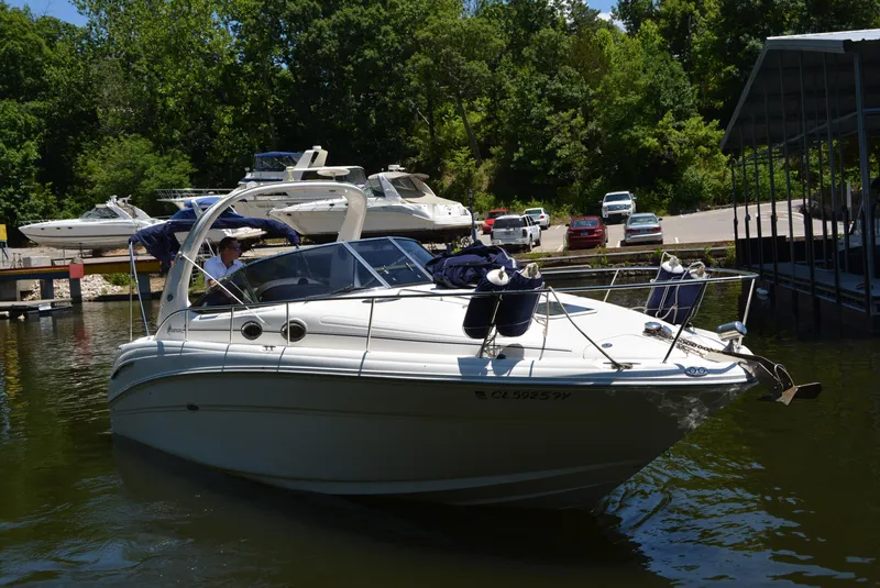 Slide: The Image of 2004 Sea Ray 300 Sundancer boat docked in a marina with lush greenery. - 9