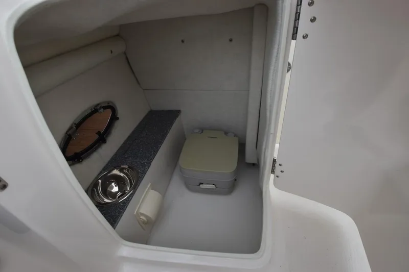 Slide: The Image of 2018 Chaparral 230 Suncoast boat interior with compact toilet and sink. - 17