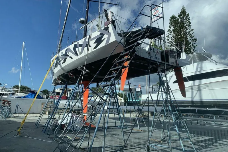Slide: The Image of 2009 Class 40 Akilaria RC2 sailboat on stands in a marina, clear sky background. - 3