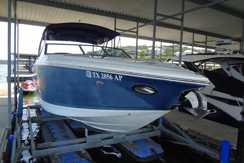 Slide: The Image of 2008 Cobalt 302 boat in dock, blue and white exterior, under covered marina. - 3