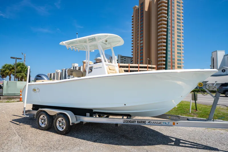 The Image of 2017 Sea Hunt Ultra 225 boat on trailer, urban backdrop, clear sky. - 0