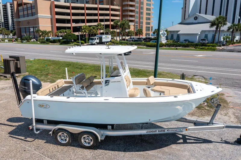 Slide: The Image of 2017 Sea Hunt Ultra 225 boat on trailer, parked near a road with buildings in background. - 1