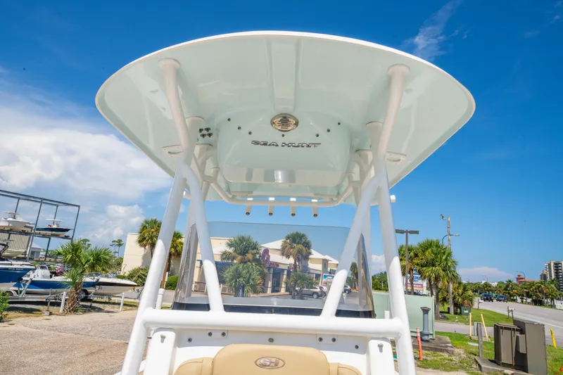 Slide: The Image of 2017 Sea Hunt Ultra 225 boat with T-top, parked outdoors under clear blue sky. - 28