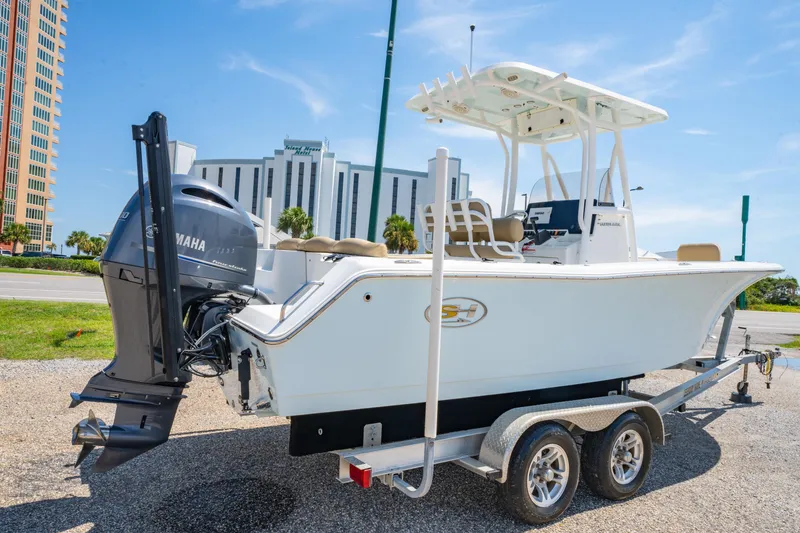 Slide: The Image of 2017 Sea Hunt Ultra 225 boat on trailer, parked near modern buildings. - 7