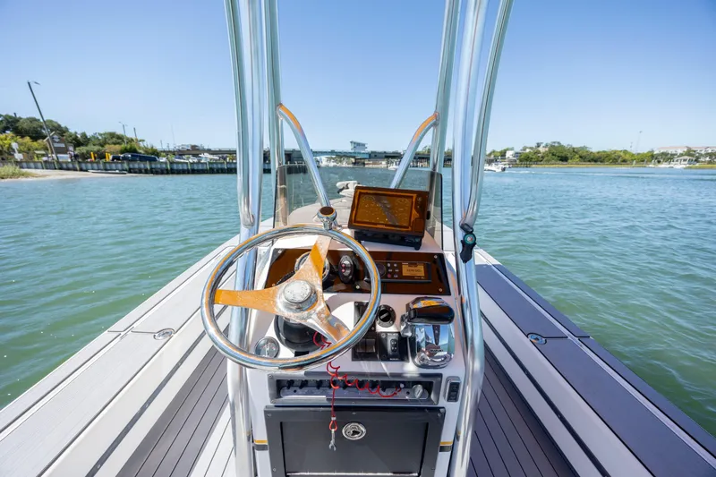 Slide: The Image of 2008 Release Tarpen Bay 21 boat dashboard with steering wheel on calm water. - 15