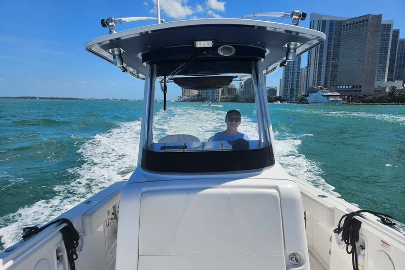 Slide: The Image of 2023 Edgewater 262CC boat cruising on turquoise water near city skyline. - 3