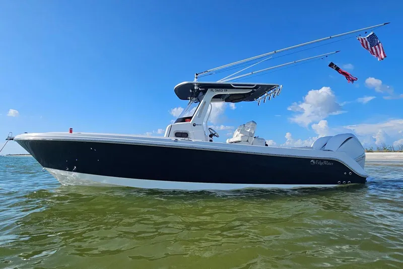 Slide: The Image of 2023 Edgewater 262CC boat on water, clear sky, flags waving, side view. - 8