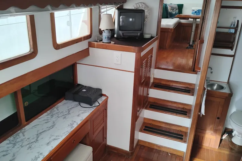 Slide: The Image of 1979 Transpac Eagle 36 Trawler interior with wood finish, TV, and compact kitchen area. - 14