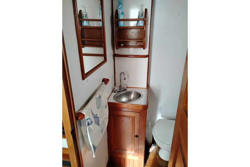 Slide: The Image of 1979 Transpac Eagle 36 Trawler bathroom with wooden cabinetry, sink, and toilet. - 17