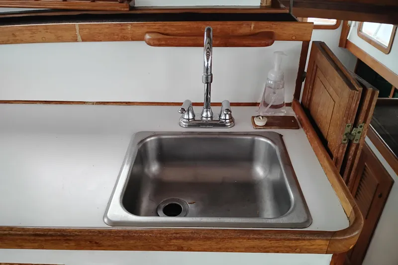 Slide: The Image of 1979 Transpac Eagle 36 Trawler kitchen sink with wooden trim and faucet. - 31