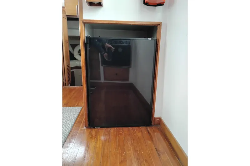 Slide: The Image of 1979 Transpac Eagle 36 Trawler interior with wooden flooring and compact refrigerator. - 32
