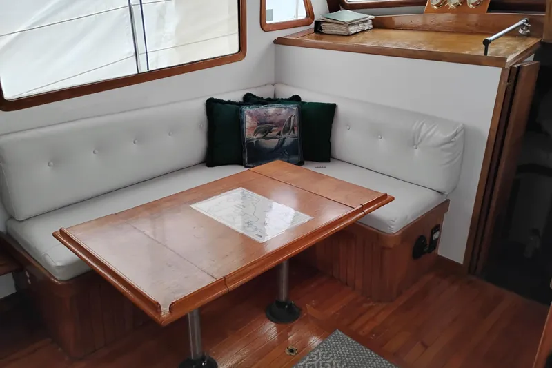 Slide: The Image of Cozy interior of 1979 Transpac Eagle 36 Trawler with white seating and wooden table. - 36