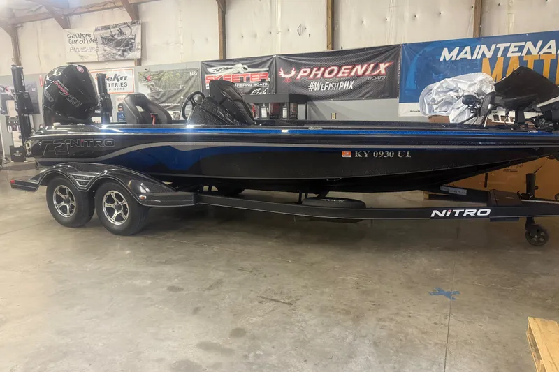 Slide: The Image of 2021 Nitro Z21 Pro boat in showroom, black and blue design, on trailer. - 3
