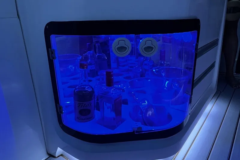 Slide: The Image of Illuminated storage compartment on 2023 Flexboat Flex 680 Explorer, featuring bottles and blue lighting. - 15