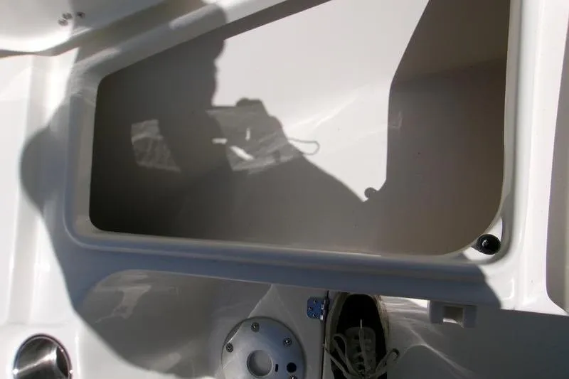 Slide: The Image of 2026 Key West 239 FS boat interior storage compartment with shadow and shoe visible. - 11